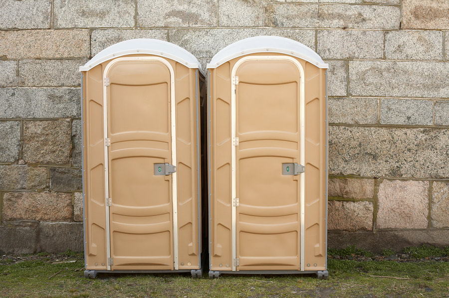 two portable toilets beside the wall